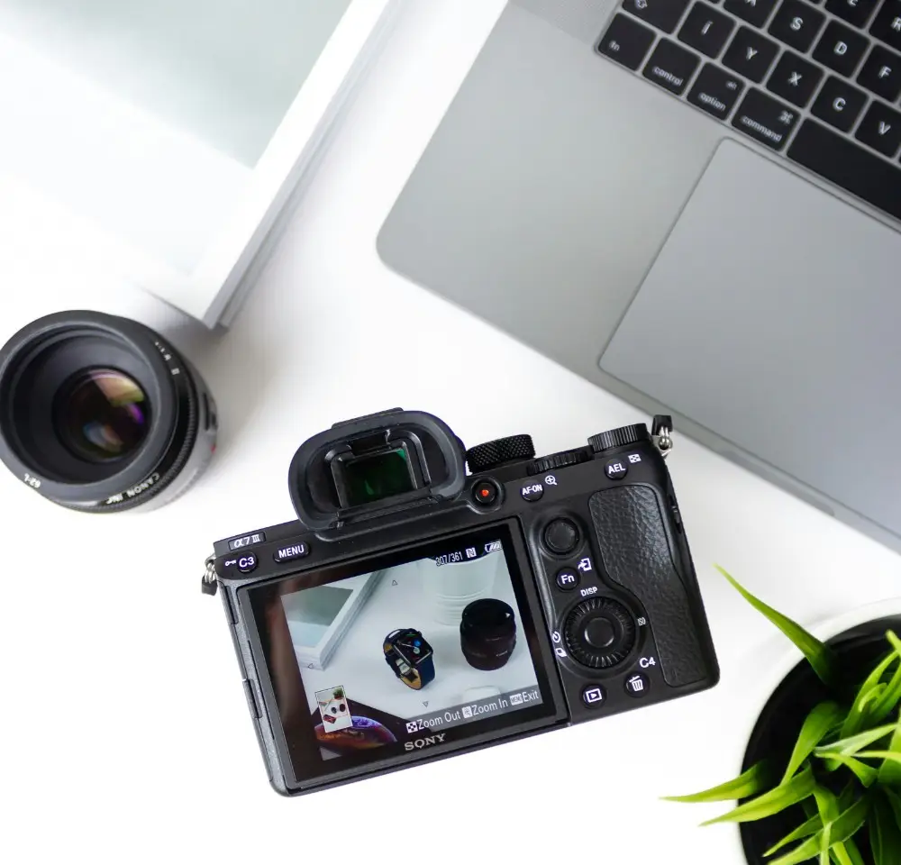 Camera, lens and macbook pro sitting on a white desk